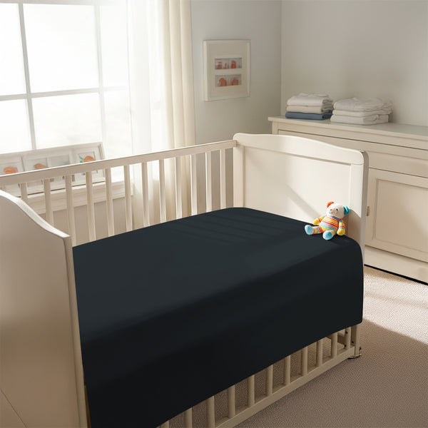 Peaceful nursery scene showing a crib with a black cotton crib flat sheet 70×100 cm