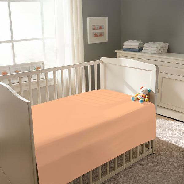 Peaceful nursery scene showing a crib with a peach cotton crib flat sheet 70×100 cm