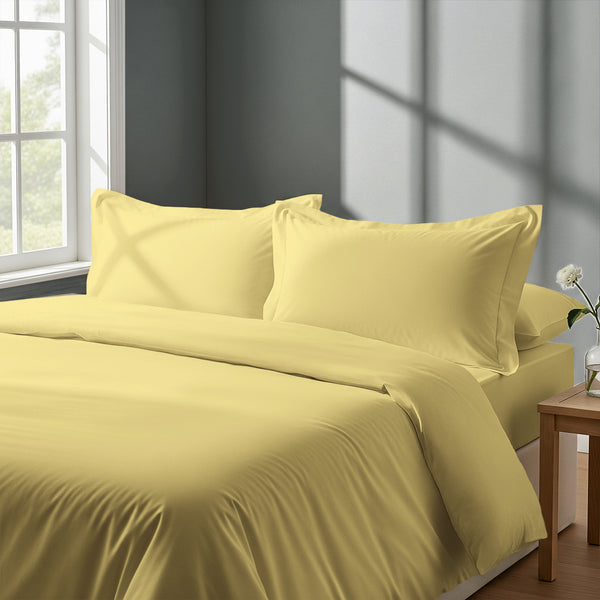Bedroom with bed dressed in royal 1000 thread count mellow yellow king duvet cover with Oxford pillowcases