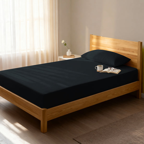Bed in a bedroom dressed with 400 thread count black eu single cotton fitted sheet
