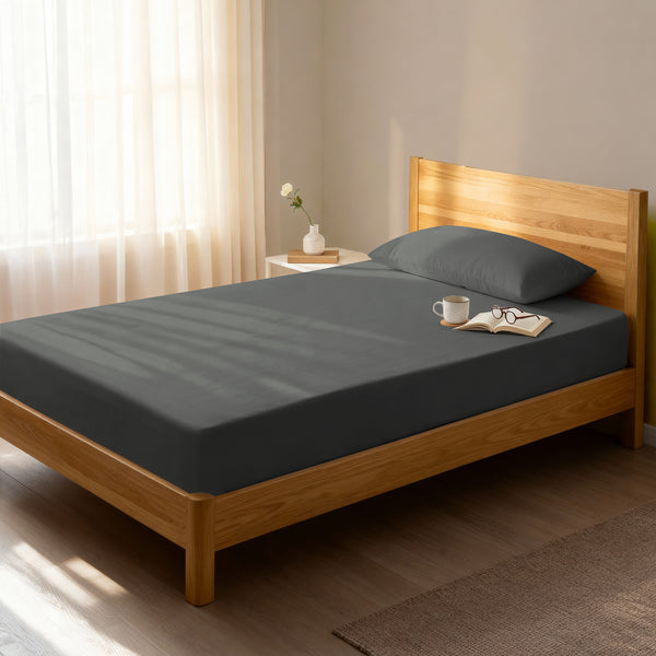 Bed in a bedroom dressed with 400 thread count dark grey single cotton fitted sheet