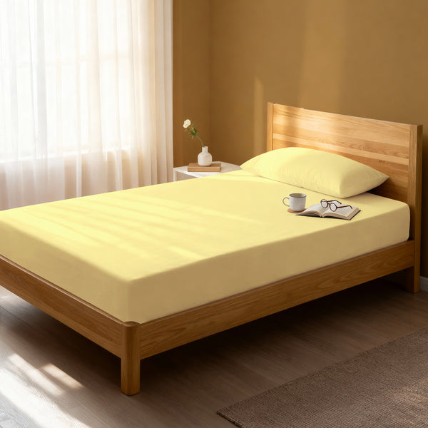 Bed in a bedroom dressed with 400 thread count mellow yellow small single cotton fitted sheet