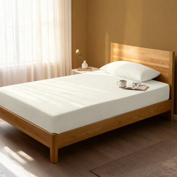Bed in a bedroom dressed with 400 thread count off white small single cotton fitted sheet