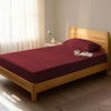 Bed in a bedroom dressed with 400 thread count rio red single cotton fitted sheet