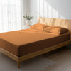 Bed in a bedroom dressed with 400 thread count Apricot Orange super king cotton fitted sheet