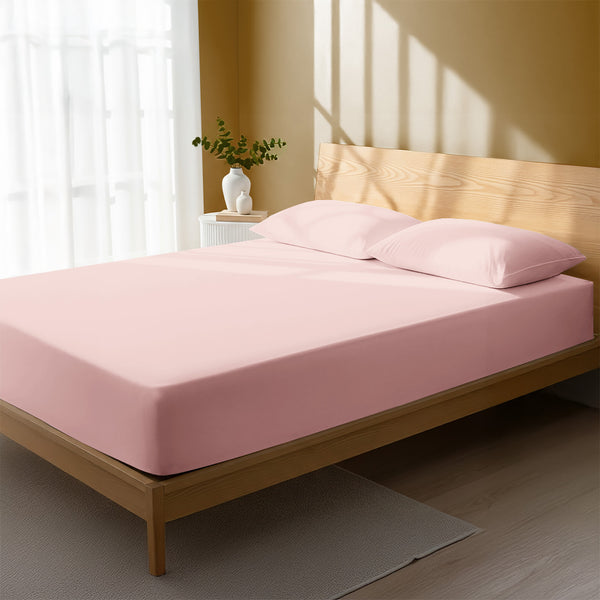 Bed in a bedroom dressed with 400 thread count light pink small double cotton fitted sheet