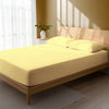 Bed in a bedroom dressed with 400 thread count mellow yellow double cotton fitted sheet